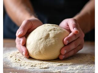 Mains d'un boulanger pétrissant la pâte à pain sur une surface en bois